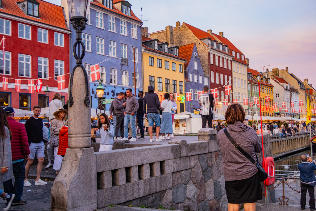 Turister vid de olikfärgade husen längs Nyhavn i Köpenhamn