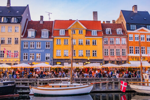 Vy över Nyhavn med sina olikfärgade hus framför båtfylld kaj, i Köpenhamn i kvällsljus