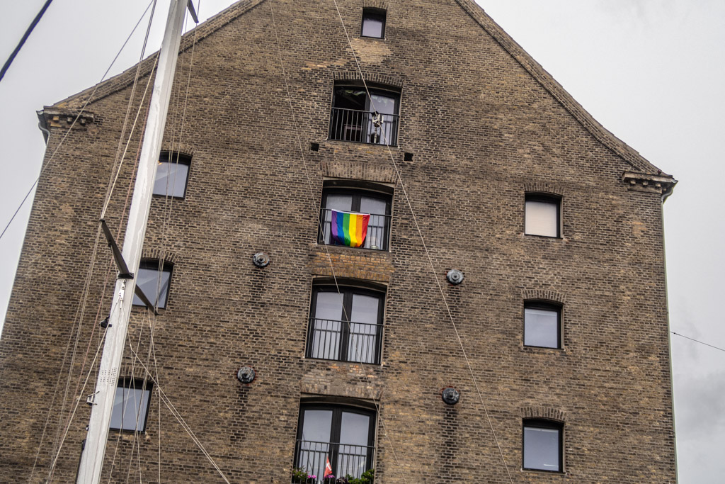 Regnbågsflagga hänger från fönstret i annars grå och dyster byggnad