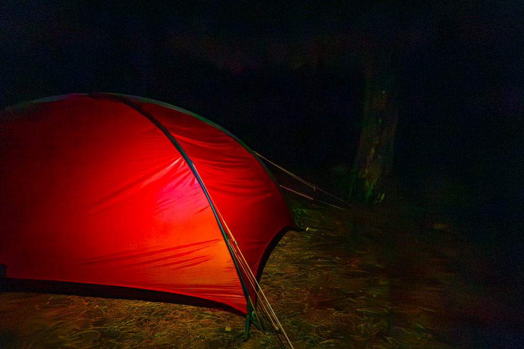 Rött tält fotat med blixt i kolsvart natt.