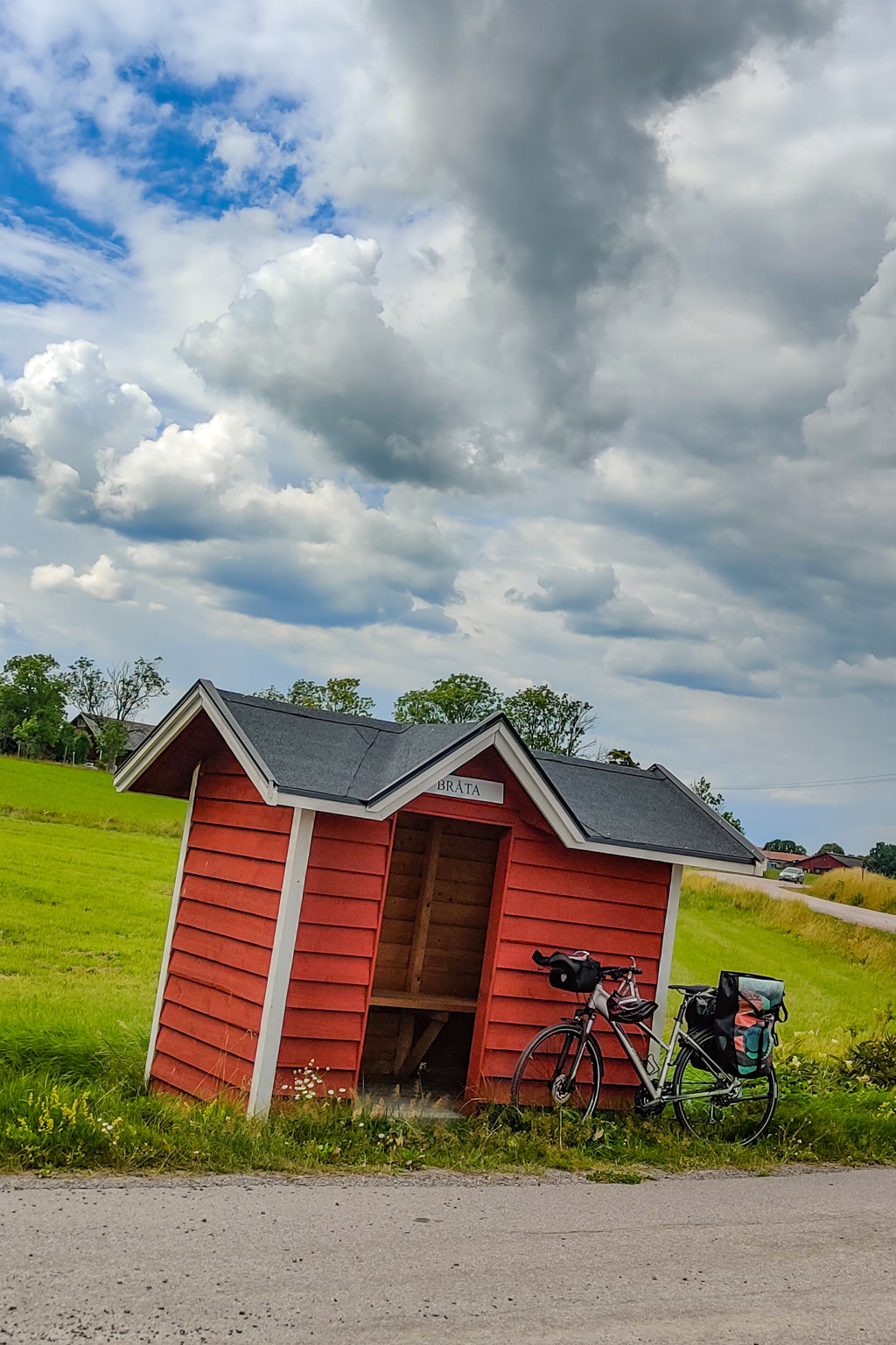 Pausar vid fin röd busshållplats under första dagen av min cykelsemester med tält.